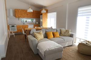a living room with a gray couch and a kitchen at Da Serra guesthouse in Porto de Mós