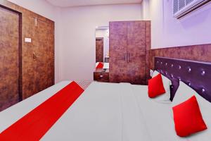 a bedroom with a large bed with red pillows at Flagship Saharsh Hotel in Patna