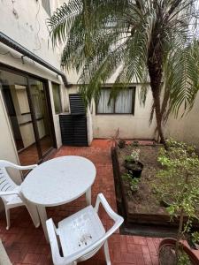 un patio con una mesa, sillas y una palmera en Hotel Yerbal en Buenos Aires