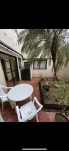 un patio con una mesa, sillas y una palmera en Hotel Yerbal en Buenos Aires