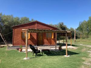 a cabin with a bench and a table and a chair at Cabaña Finca el Oasis en Jáchal, San Juan in San José de Jáchal