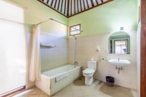 y baño con bañera, aseo y lavamanos. en Taman Surgawi Resort & Spa, en Jasri
