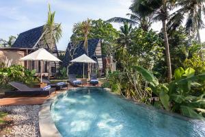 a swimming pool in front of a villa at TUJUH Angel by GenuineHost in Ubud