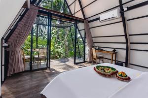a room with a bed in a room with a balcony at TUJUH Angel by GenuineHost in Ubud