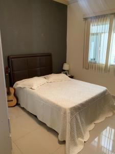 a bedroom with a bed with a white blanket on it at Casa Temporada Charres in Caparaó Velho