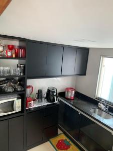 a small kitchen with black cabinets and a microwave at Casa Temporada Charres in Caparaó Velho