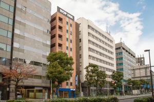 an office building on a city street with trees at Hop Inn Tokyo Iidabashi in Tokyo