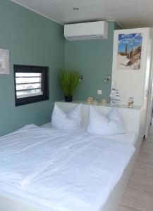 1 dormitorio con 1 cama blanca grande y almohadas blancas en Hausboot Albatros, en Mücheln