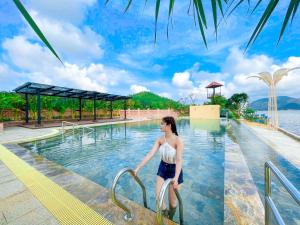 a woman walking down a hand rail in a swimming pool at Seagate Bungalow Quy Nhon in Quy Nhon