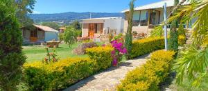 una casa con un jardín con flores amarillas y moradas en CABAÑA LOS JUANES en Sutamarchán