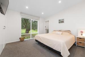 a white bedroom with a bed and a window at Secluded Seaside Hideaway in Rye