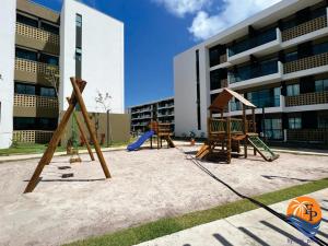 une aire de jeux en face d'un bâtiment avec deux balançoires dans l'établissement Mana Beach Pono by Flats Prime, à Porto de Galinhas