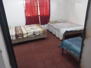 two beds in a room with red curtains at Rancho santa cecilia in Sonsonate