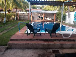 a patio with two chairs and a table next to a pool at Rancho santa cecilia in Sonsonate