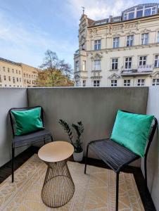two chairs and a table on a balcony with a building at Modern building with vertical garden & 2 bedrooms in Berlin
