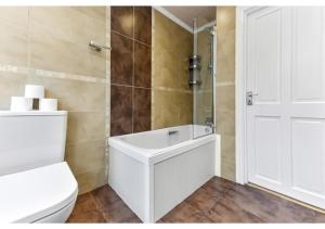 y baño blanco con aseo y ducha. en Homey and Pleasant 3BD en Londres