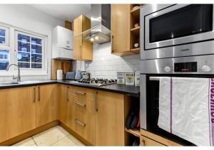 una cocina con estufa y microondas en Homey and Pleasant 3BD, en Londres