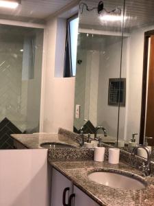 uma casa de banho com 2 lavatórios e um espelho grande em Apartamento Central Park Oktoberfest em Blumenau
