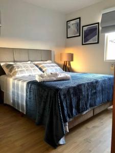 um quarto com uma cama grande e um cobertor azul em Apartamento Central Park Oktoberfest em Blumenau