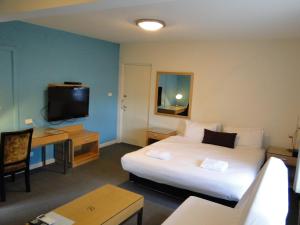 a hotel room with a bed and a desk and a tv at Brighton Serviced Apartments in Melbourne