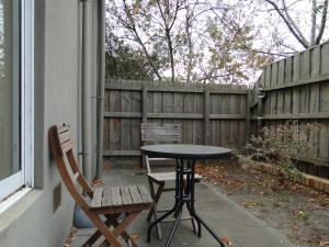 a table and chair on a patio with a fence at Brighton Serviced Apartments in Melbourne