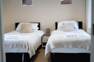 dos camas sentadas una al lado de la otra en un dormitorio en Family & Business Stays In RG2 - Sleeps Up to 12!, en Reading