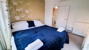 Un dormitorio con una cama azul con toallas. en Family & Business Stays In RG2 - Sleeps Up to 12!, en Reading