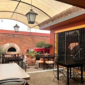 een patio met tafels en stoelen en een pizza-oven bij Hotel Art Gallery Casona de los Milagros in Colima