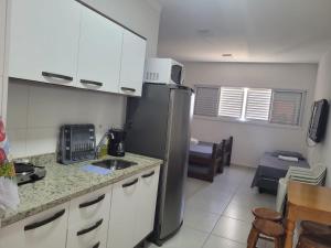 uma cozinha com um frigorífico de aço inoxidável num quarto em Estúdio Mobiliado Condomínio da Fé Canção Nova apto 02 em Cachoeira Paulista