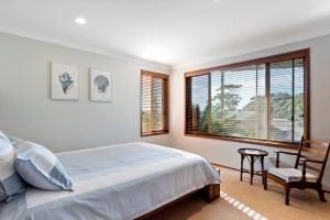 a bedroom with a bed and a chair and a window at Daybreak by Experience Jervis Bay in Vincentia