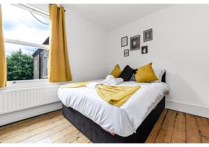 a bedroom with a bed with yellow curtains and a window at Handsome Family Home Peaceful, Next to Park in London