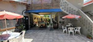 an outdoor patio with tables and chairs and umbrellas at Hostel Megaró in Santa Teresita
