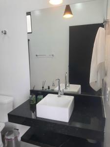 y baño con lavabo blanco y espejo. en Pousada Lobo Guará en São João Batista do Glória