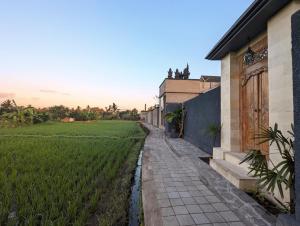 un camino junto a un campo de hierba junto a un edificio en Villa Na-Na Ubud, en Ubud