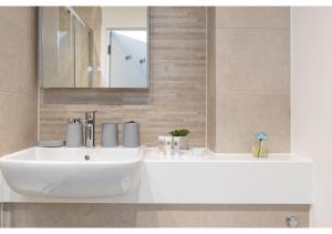 uma casa de banho com um lavatório branco e um espelho. em Beckenham Beauty: Modern 1-Bedroom Abode em Beckenham