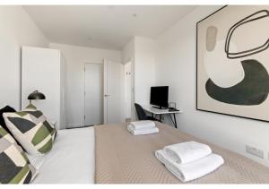 a white bedroom with a bed and a desk at Beckenham Beauty: Modern 1-Bedroom Abode in Beckenham