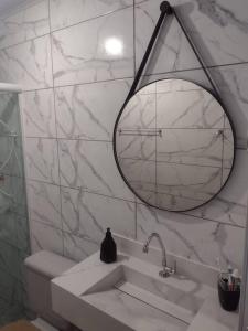 Baño blanco con lavabo y espejo en casa aconchegante em Ubatuba en São Francisco do Sul