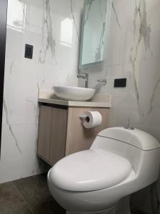 a bathroom with a white toilet and a sink at LAS TOLAS HOTEL-RESTAURANTE in Pallatanga