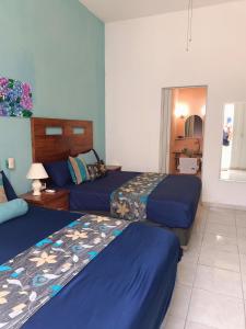 Habitación de hotel con 2 camas con sábanas azules en Casa las Flores, en Puerto Vallarta