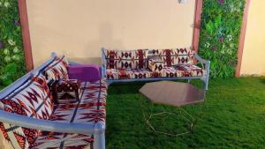 eine Couch und ein Stuhl auf dem Rasen in der Unterkunft شاليهات يارا القيروان in Riad