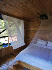a bed in a wooden room with a window at Villas del Rio Glamping in San Francisco