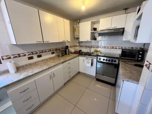 a white kitchen with white cabinets and appliances at Casa Colibrí - Tongoy in Tongoy