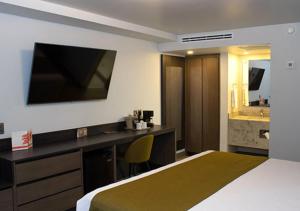 a hotel room with a bed and a desk and a sink at Hotel Calafia in Mexicali