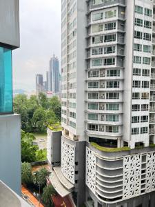 Cette chambre offre une vue sur un grand bâtiment blanc doté d'un toit vert. dans l'établissement Summer suites KLCC by cozy stay, à Kuala Lumpur