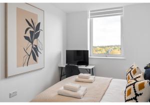 ein Schlafzimmer mit einem Bett mit Handtüchern darauf in der Unterkunft Sophisticated Living: 1-BR Flat in Beckenham in Beckenham