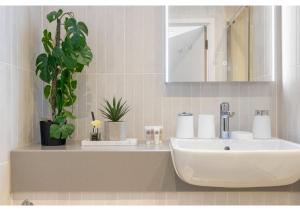 a bathroom with a sink and a mirror and a plant at Sophisticated Living: 1-BR Flat in Beckenham in Beckenham