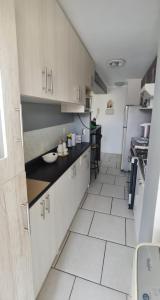 a large kitchen with white tile floors and cabinets at Arica verano y surf Dpto completo 2 habitaciones in Arica