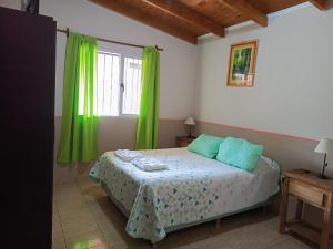 a bedroom with a bed with green curtains and a window at Hospedaje Fliar En Gobernador Gregores in Gobernador Gregores