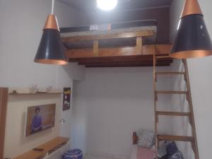 casa aconchegante em Ubatuba في ساو فرانسيسكو دو سول: سرير بطابقين في غرفة بها مصباحين وسلم
