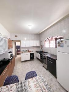 a kitchen with white appliances and a table and chairs at Casa em Mongaguá Plataforma in Mongaguá